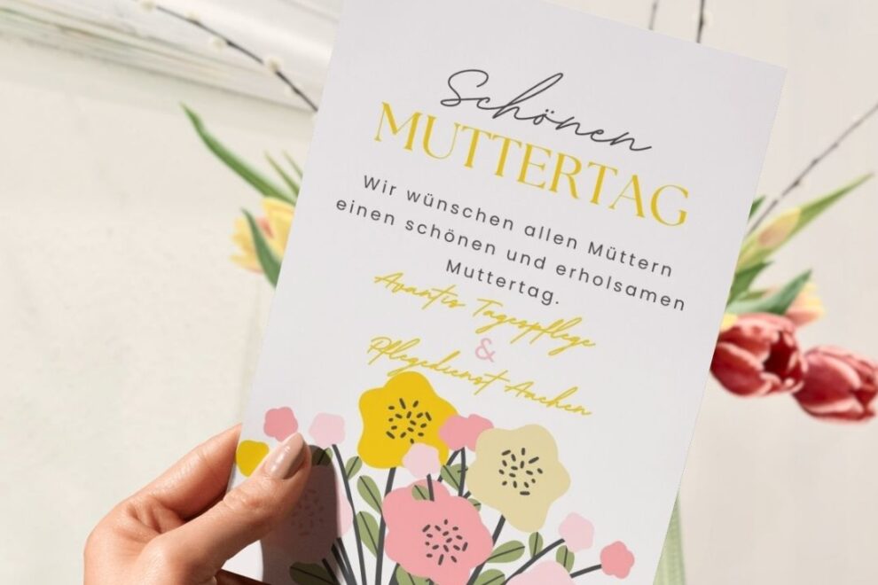Hand hält eine Muttertagskarte von Avantis Tagespflege und Pflegedienst Aachen mit Blumenmotiv.